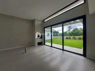 Sala de estar com grande porta de vidro abrindo para um jardim gramado.
