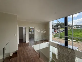 Hall de entrada com piso de madeira e guarda-corpo de vidro que se abre para a vista externa.