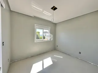 Ambiente interno de uma sala de estar com paredes brancas e piso claro.