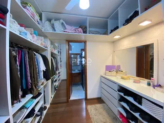 Armários brancos com roupas organizadas preenchem a parede de um cômodo.