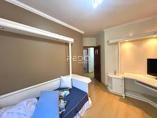 Quarto com paredes bege e piso de madeira clara.