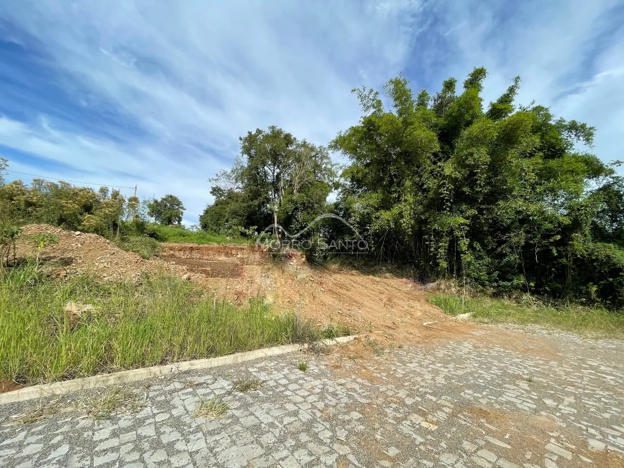 Vista externa de uma área de terra com vegetação densa ao fundo.