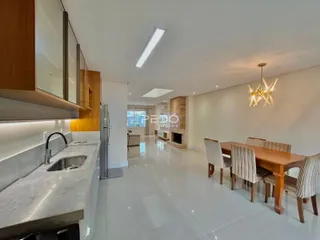 Interior de uma sala de estar com cozinha e área de jantar em um imóvel no Brasil.