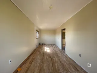 Um corredor longo com piso de madeira clara.