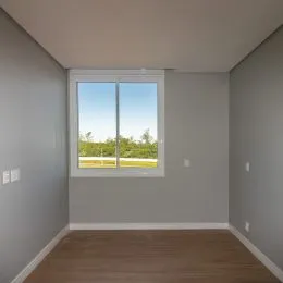 Vista de uma janela em um cômodo interno com piso de madeira.