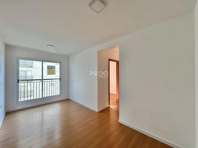 Sala de estar com piso de madeira e porta de vidro voltada para a varanda.