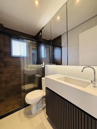 Banheiro moderno com box de vidro e bancada de mármore.