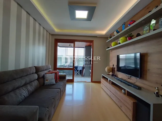 Sala de estar com sofá cinza e piso de madeira clara.