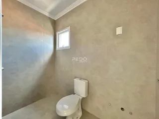 Foto de um banheiro com paredes em tom neutro e vaso sanitário branco.