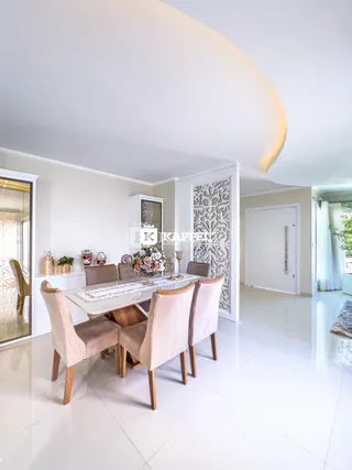 Uma sala de jantar clara com mesa e cadeiras em um ambiente bem iluminado.