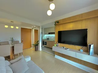 Sala de estar moderna com piso de madeira clara e televisão de parede.
