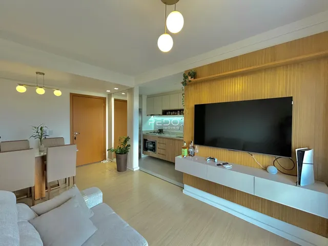 Sala de estar moderna com piso de madeira clara e televisão de parede.