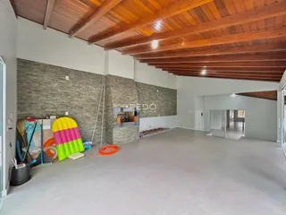 Interior de uma grande sala com teto de madeira exposto e paredes texturizadas.