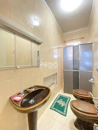 Foto de um banheiro com azulejos claros e pia de bronze.