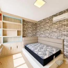 Quarto com cama e parede de tijolos aparentes.