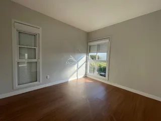 Foto de um ambiente interno com piso de madeira e janelas.