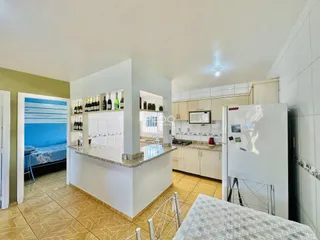 Interior de uma cozinha aberta com armários brancos e piso de cerâmica.