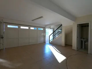 Vista interna de um espaço amplo com porta de garagem e escadaria.