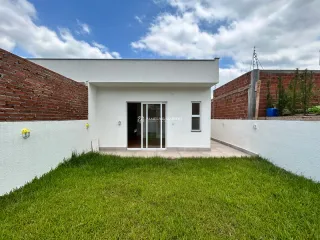 Fachada externa de uma residência com paredes brancas e detalhes em tijolo vermelho.