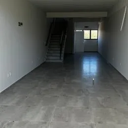 Foto de um corredor interno com piso escuro.