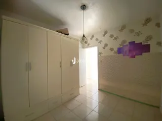 Uma vista de um corredor interno com armários brancos e piso de cerâmica.