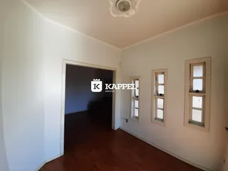 Hall de entrada com piso de madeira e janelas na parede.
