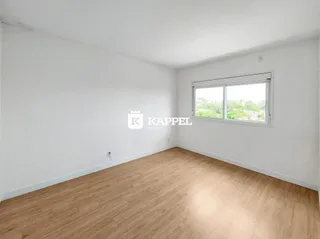 Uma sala ampla com piso de madeira clara e uma janela.