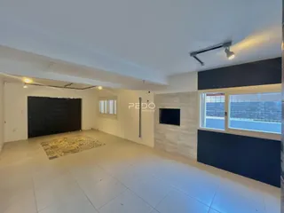 Ambiente interno amplo com piso claro e parede escura.