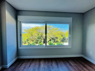 Sala de estar com grande janela que oferece vista para a vegetação externa.