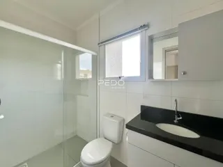 Banheiro moderno com box de vidro e louças brancas.