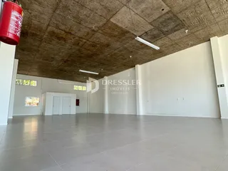 Espaço interno amplo com piso claro e teto de concreto aparente.