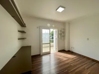 Foto do interior de uma sala com piso de madeira e porta de entrada.