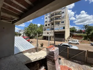 Vista externa de um imóvel em construção com uma edificação residencial ao fundo.