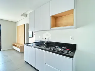 A cozinha apresenta armários brancos e bancada escura com eletrodomésticos embutidos.