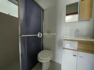 Foto de um banheiro interno com louças sanitárias e armários de madeira.