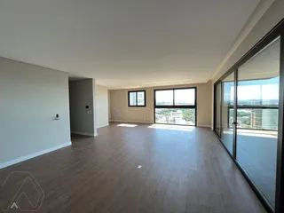 Sala ampla com piso de madeira e vista da cidade.