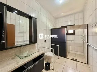 Banheiro com revestimento branco e piso cerâmico.