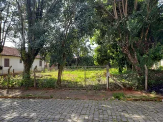 Vista externa da propriedade com vegetação e cerca de madeira.