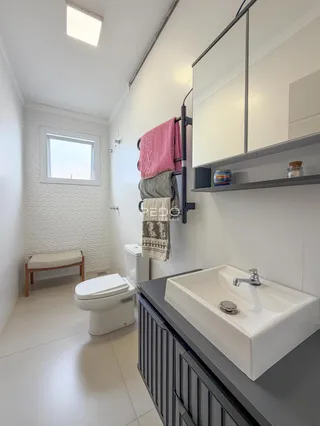 Foto interna de um banheiro moderno com revestimento cerâmico e bancada escura.