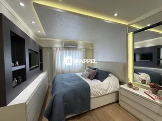 Quarto com cama grande e painel de TV em ambiente moderno.