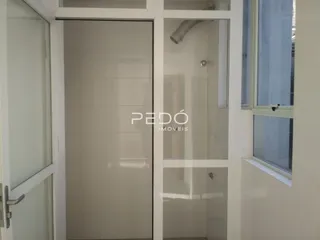 Interior de um banheiro com paredes brancas e divisória de vidro.