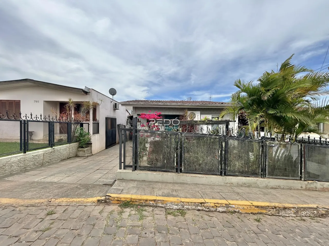 Fachada de uma residência com cerca de ferro e calçada em Lajeado, Brasil.