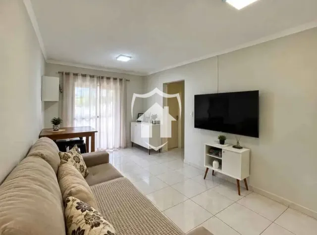 Sala de estar com sofá e televisão montada na parede.
