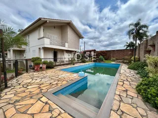 Foto da fachada de uma casa com piscina e área externa pavimentada.
