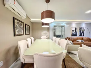 Uma sala de jantar com mesa e cadeiras brancas em um imóvel no Brasil.