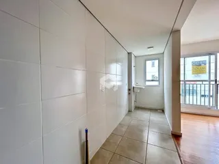 Corredor interno com revestimento de cerâmica e paredes brancas.