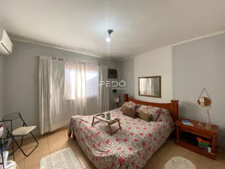 Quarto com cama de madeira e cortinas brancas em um imóvel no Brasil.