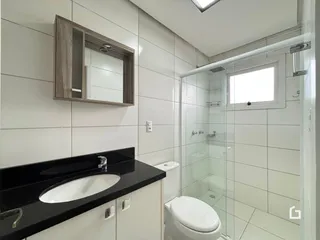 Foto de um banheiro com box de vidro e revestimento branco.