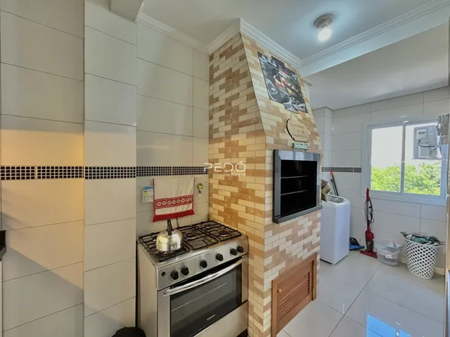 Uma cozinha com revestimento de tijolo aparente e piso cerâmico.