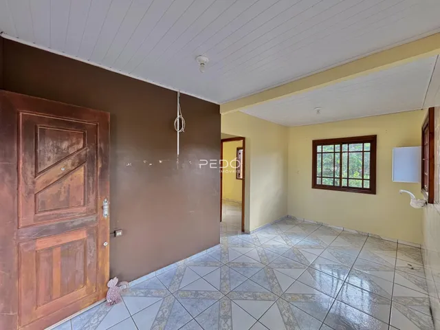 Hall de entrada com porta de madeira e piso de cerâmica em uma residência.